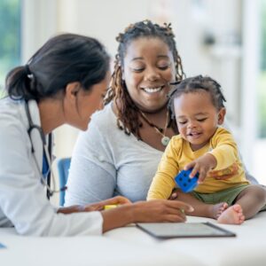 Doctor and mom using shared decision-making to make decision for baby as baby plays with a blocl